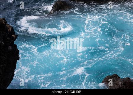 Raue Meere wirbeln über vulkanisches Gestein an der Küste von Playa San Juan, Teneriffa, Kanarische Inseln, Spanien Stockfoto