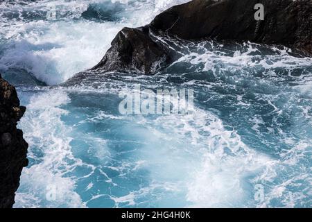 Raue Meere wirbeln über vulkanisches Gestein an der Küste von Playa San Juan, Teneriffa, Kanarische Inseln, Spanien Stockfoto