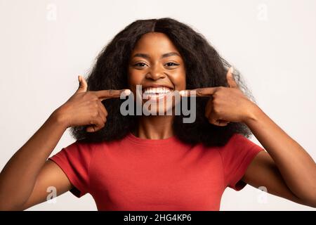 Zahngesundheit. Schöne Junge Afroamerikanische Frau, Die Auf Ihr Lächeln Zeigt Stockfoto
