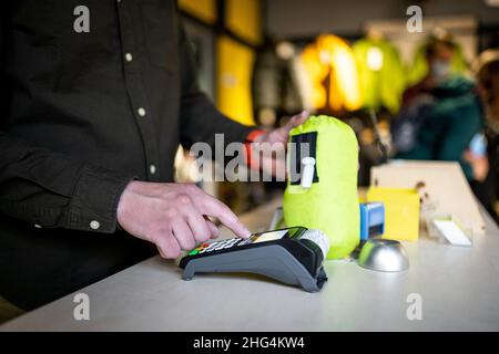 Der Verkäufer hält das Zahlungsterminal, während er den Beleg für den Abschluss des Kaufs hält. Nahaufnahme der Hände. Konzept von NFC, Geschäfts- und Bankgeschäften Stockfoto