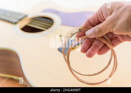 Der Musiker ersetzt die neuen Gitarrensaiten für seine Gitarre Stockfoto