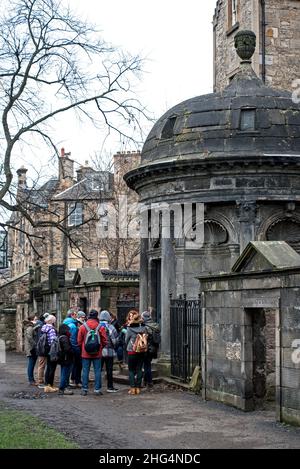 Touristen auf einem geführten Rundgang versammeln sich am Grab von Sir George Mackenzie von Rosehaugh (1636–1691) in Greyfriars Kirkyard, Edinburgh, Schottland, Großbritannien. Stockfoto