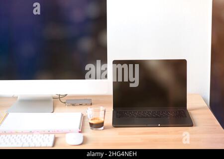 Nahaufnahme des Arbeitsplattes in einem Büro mit Holztisch und Laptop-Verlegung, Ort der Arbeit. Ein komfortabler Arbeitsplatz mit Laptop Espresso Smartphone Notizblock Papier Stift Brillen Maus darauf legen. Hebräische Tastatur. Hochwertige Fotos Stockfoto