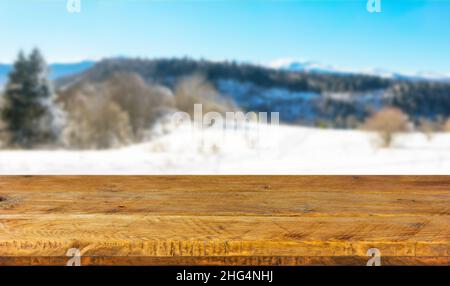 Ein Holzbrett, eine leere Tischplatte und ein verschwommener Hintergrund mit einer Winterlandschaft. Modell zur Präsentation des Produkts. Stockfoto