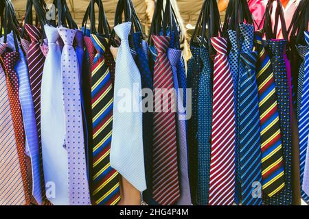 Große Auswahl an bunten Krawatten hängen in den Verkauf auf dem Straßenmarkt. Viele verschiedene Muster bunte Krawatten hängen auf Kleiderständer. Farbe Stockfoto