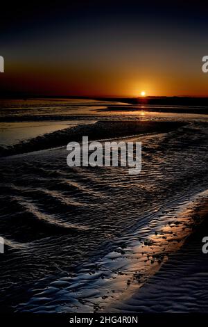 Baie de Somme, le Hourdel, chenal à marée basse, blockhaus, coucher de Soleil sur la mer , sable et balise. Stockfoto