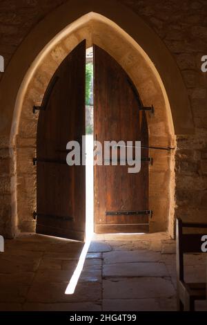 Alte Kapelle gewölbte Holztür leicht geöffnet lassen in einem Strahl von Sonnenlicht Stockfoto