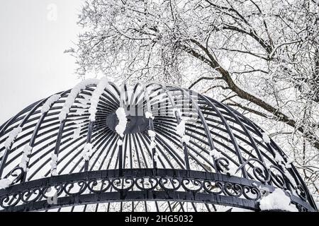 Schwarzes Metallgitter im Winter mit Schnee bedeckt. Schneefall- und Winterwetterkonzept. Stockfoto