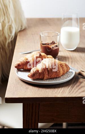 Zwei Schokoladencroissants mit Milch zum Frühstück. Stockfoto