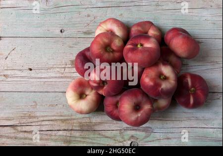 Isolierte rote Frucht namens Flat Peach, Prunus persica platycarpa, auch bekannt als Donut Peach Donut Peach Saturn Pfirsich auf Holz Hintergrund Stockfoto