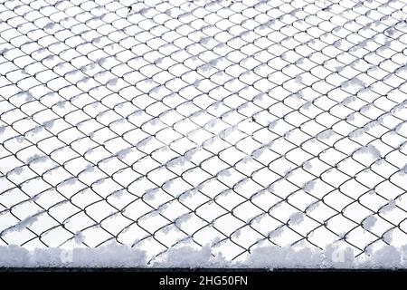 Schwarzes Metallgitter im Winter mit Schnee bedeckt. Schneefall- und Winterwetterkonzept. Stockfoto