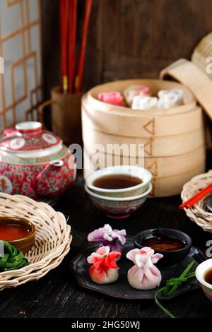 Jiaozi, Har Gow und Siu Mai, wunderschöne chinesische, farbenfrohe, gedämpfte Knödel. Traditionelles Dim Sum-Set mit Tee Stockfoto