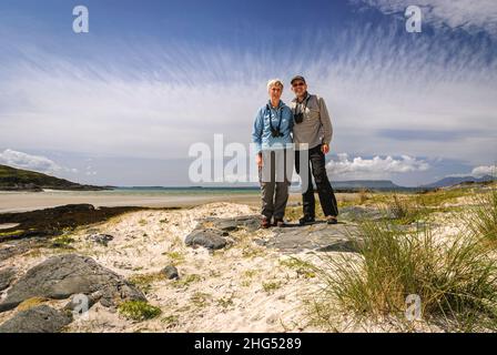 Ein Sommer-HDR-Bild eines reifen Paares, das am Silver Sands of Morar an der Westküste Schottlands steht. 14. Juni 2011 Stockfoto