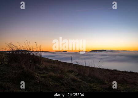 Ein Winter-HDR einer Wolkeninversion und eines Sonnenuntergangs vom Butter Tubs Pass mit Ingleborough in der Ferne, Wensleydale, Yorkshire, England. 14. Januar 2022 Stockfoto