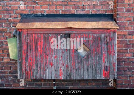 Alter, hölzerner und verwitterter Feuerwehreinbauschrank Stockfoto