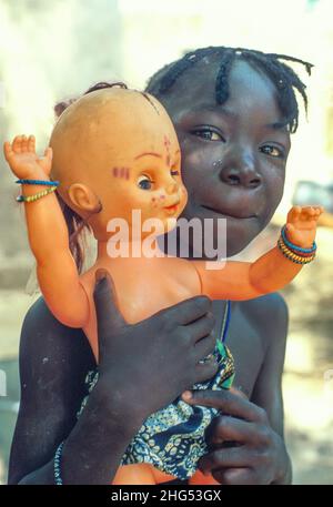 Porträt eines frechen jungen Bozo-Mädchens, das eine weiße Puppe trägt. Dagua Womina, Mali, Westafrika Stockfoto