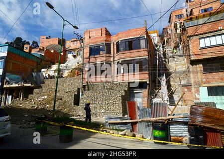 La Paz, Bolivien: Kommunale Arbeiter stabilisieren einen Hügel und beschädigte Häuser mit Käfigen gefüllt mit Felsen/Gabionen an einem Standort im Bezirk Tembladerani/Cotahuma. Unbefugte Ausgrabungen und Erdbewegungen durch einen der Grundstückseigentümer führten zum Einsturz eines Teils des Hügels. Viele von La Paz Hanggegenden wurden in instabilen Gebieten ohne entsprechende Genehmigungen oder Gebäudekontrollen gebaut. Senkungen und Erosion, die Erdrutsche und Einsturz von Häusern verursachen, sind häufig, besonders in der Regenzeit. Bei diesem Vorfall mussten 2 Häuser abgerissen werden, 6 weitere wurden stark betroffen. Stockfoto