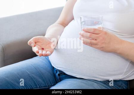 Schwangere mit Pillen mit Eisen FE Ferrum Element in der Hand. Nahrungsergänzungsmittel. Vitaminkapseln Stockfoto