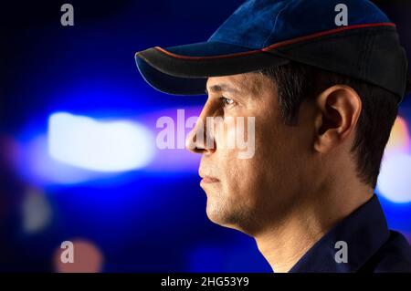 Zugeschnittenes Porträt eines Polizisten, der allein stand und nachts in eine Kontrolle starrte Stockfoto