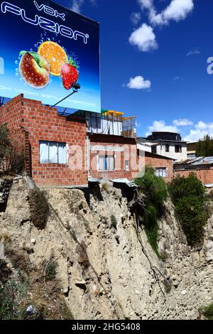 Backsteinhäuser am Rande einer instabilen Erdklippe / Schlucht im zentralen Viertel Miraflores mit Blick auf die Avenida del Poeta, La Paz, Bolivien. Viele von La Paz Hanggegenden wurden in instabilen Gebieten und ohne entsprechende Genehmigungen oder Baukontrollen gebaut. Senkungen und Erdrutsche, die zum Einsturz von Häusern führen, sind häufig, besonders in der Regenzeit. Stockfoto