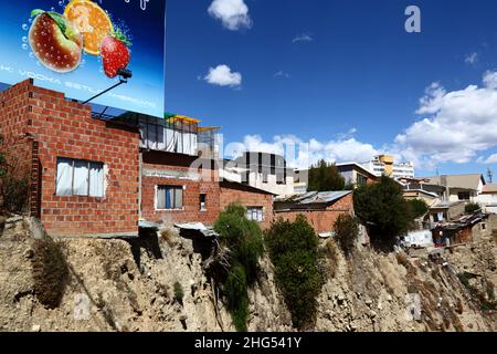 Backsteinhäuser am Rande einer instabilen Erdklippe / Schlucht im zentralen Viertel Miraflores mit Blick auf die Avenida del Poeta, La Paz, Bolivien. Viele von La Paz Hanggegenden wurden in instabilen Gebieten und ohne entsprechende Genehmigungen oder Baukontrollen gebaut. Senkungen und Erdrutsche, die zum Einsturz von Häusern führen, sind häufig, besonders in der Regenzeit. Stockfoto