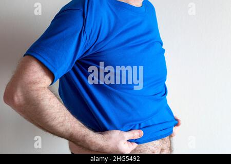 Mann kleidet sich, probiert ein T-Shirt an. Mann trägt T-Shirt und Jeans, stehend. Konzept passend beim Anprobieren von Kleidung Stockfoto