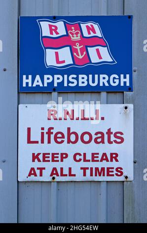 Schilder vor dem RNLI Rettungsbootschuppen an der Nord-Norfolk-Küste bei Cart Gap, Happisburgh, Norfolk, England, Großbritannien. Stockfoto