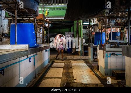 Bangkok, Thailand. 18th Januar 2022. Ein Arbeiter trägt Schweinekörper auf dem Rücken in einen Markt, auf dem sie geschlachtet und verkauft werden.Arbeiter auf dem Großmarkt Bangkok Noi bereiten am 18. Januar 2022 frisch geschlachtetes Schweinefleisch zum Verkauf vor. Aufgrund von Lieferengpässen, Marktspekulationen und einem möglichen Ausbruch der Afrikanischen Schweinepest steigen die Schweinefleischkosten in Thailand in die Höhe, was den Preis für Grundnahrungsmittel in die Höhe schiessen lässt. Die schnelle Inflation hat zu einem plötzlichen landesweiten Anstieg von Lebensmitteln von der Straße bis zum Supermarkt geführt. Kredit: SOPA Images Limited/Alamy Live Nachrichten Stockfoto