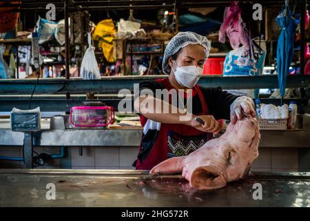 Bangkok, Thailand. 18th Januar 2022. Ein Arbeiter rasiert einem Schwein den Kopf, bevor es geschlachtet und auf dem Markt verkauft wird.Arbeiter auf dem Großmarkt Bangkok Noi bereiten am 18. Januar 2022 frisch geschlachtetes Schweinefleisch zum Verkauf vor. Aufgrund von Lieferengpässen, Marktspekulationen und einem möglichen Ausbruch der Afrikanischen Schweinepest steigen die Schweinefleischkosten in Thailand in die Höhe, was den Preis für Grundnahrungsmittel in die Höhe schiessen lässt. Die schnelle Inflation hat zu einem plötzlichen landesweiten Anstieg von Lebensmitteln von der Straße bis zum Supermarkt geführt. Kredit: SOPA Images Limited/Alamy Live Nachrichten Stockfoto