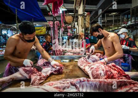 Bangkok, Thailand. 18th Januar 2022. Die Arbeiter schlachten Schweinefleisch, bevor es auf dem Markt verkauft wird.die Arbeiter auf dem Großmarkt Bangkok Noi bereiten am 18. Januar 2022 frisch geschlachtetes Schweinefleisch zum Verkauf vor. Aufgrund von Lieferengpässen, Marktspekulationen und einem möglichen Ausbruch der Afrikanischen Schweinepest steigen die Schweinefleischkosten in Thailand in die Höhe, was den Preis für Grundnahrungsmittel in die Höhe schiessen lässt. Die schnelle Inflation hat zu einem plötzlichen landesweiten Anstieg von Lebensmitteln von der Straße bis zum Supermarkt geführt. Kredit: SOPA Images Limited/Alamy Live Nachrichten Stockfoto