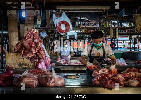 Bangkok, Thailand. 18th Januar 2022. Die Arbeiter schlachten Schweinefleisch, bevor es auf dem Markt verkauft wird.die Arbeiter auf dem Großmarkt Bangkok Noi bereiten am 18. Januar 2022 frisch geschlachtetes Schweinefleisch zum Verkauf vor. Aufgrund von Lieferengpässen, Marktspekulationen und einem möglichen Ausbruch der Afrikanischen Schweinepest steigen die Schweinefleischkosten in Thailand in die Höhe, was den Preis für Grundnahrungsmittel in die Höhe schiessen lässt. Die schnelle Inflation hat zu einem plötzlichen landesweiten Anstieg von Lebensmitteln von der Straße bis zum Supermarkt geführt. Kredit: SOPA Images Limited/Alamy Live Nachrichten Stockfoto