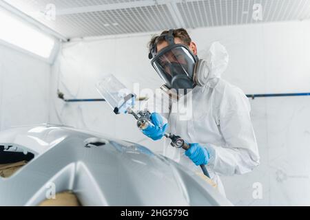 Automechaniker malt Autostoßstange mit Spritzpistole Stockfoto