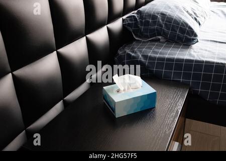 Weißes Tuch in blauer Papierbox auf dem Nachttisch im Schlafzimmer Stockfoto