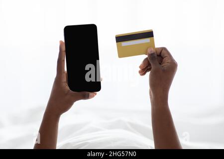 Schwarze Dame Hände halten Handy und Kreditkarte Stockfoto