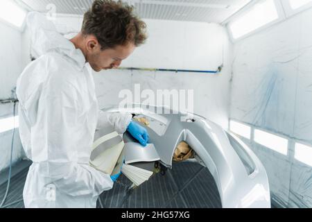 Männlicher Kolorist, der die Farbe des Autostoßfängers mit farblich passenden Mustern auswählt Stockfoto