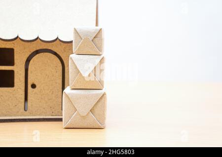 Stapel von kleinen Paketen vor einem Miniatur-Hausmodell. Sopping- und Lieferkonzept. Stockfoto