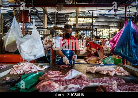 Bangkok, Thailand. 18th Januar 2022. Ein Arbeiter schlachtet Schweinefleisch, bevor es auf dem Markt verkauft wird.Arbeiter auf dem Großmarkt Bangkok Noi bereiten am 18. Januar 2022 frisch geschlachtetes Schweinefleisch zum Verkauf vor. Aufgrund von Lieferengpässen, Marktspekulationen und einem möglichen Ausbruch der Afrikanischen Schweinepest steigen die Schweinefleischkosten in Thailand in die Höhe, was den Preis für Grundnahrungsmittel in die Höhe schiessen lässt. Die schnelle Inflation hat zu einem plötzlichen landesweiten Anstieg von Lebensmitteln von der Straße bis zum Supermarkt geführt. (Foto von Matt Hunt/SOPA Images/Sipa USA) Quelle: SIPA USA/Alamy Live News Stockfoto