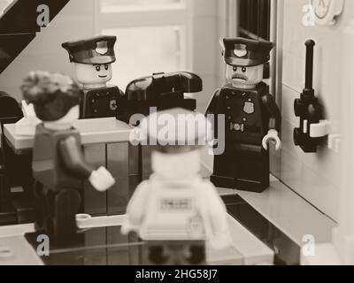 Tambow, Russische Föderation - 02. August 2021 vier Lego-Polizisten, die in der Nähe eines alten Telefons in einer Polizeistation eine Diskussion führen. Schwarz und Weiß. Stockfoto