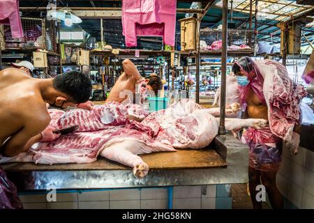 Bangkok, Thailand. 18th Januar 2022. Die Arbeiter schlachten Schweinefleisch, bevor es auf dem Markt verkauft wird.die Arbeiter auf dem Großmarkt Bangkok Noi bereiten am 18. Januar 2022 frisch geschlachtetes Schweinefleisch zum Verkauf vor. Aufgrund von Lieferengpässen, Marktspekulationen und einem möglichen Ausbruch der Afrikanischen Schweinepest steigen die Schweinefleischkosten in Thailand in die Höhe, was den Preis für Grundnahrungsmittel in die Höhe schiessen lässt. Die schnelle Inflation hat zu einem plötzlichen landesweiten Anstieg von Lebensmitteln von der Straße bis zum Supermarkt geführt. (Foto von Matt Hunt/SOPA Images/Sipa USA) Quelle: SIPA USA/Alamy Live News Stockfoto