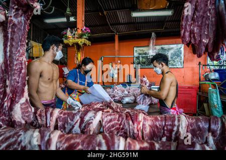 Bangkok, Thailand. 18th Januar 2022. Arbeiter schlachten und verpacken Schweinefleisch, bevor es auf dem Markt verkauft wird.Arbeiter auf dem Großmarkt Bangkok Noi bereiten am 18. Januar 2022 frisch geschlachtetes Schweinefleisch zum Verkauf vor. Aufgrund von Lieferengpässen, Marktspekulationen und einem möglichen Ausbruch der Afrikanischen Schweinepest steigen die Schweinefleischkosten in Thailand in die Höhe, was den Preis für Grundnahrungsmittel in die Höhe schiessen lässt. Die schnelle Inflation hat zu einem plötzlichen landesweiten Anstieg von Lebensmitteln von der Straße bis zum Supermarkt geführt. (Foto von Matt Hunt/SOPA Images/Sipa USA) Quelle: SIPA USA/Alamy Live News Stockfoto