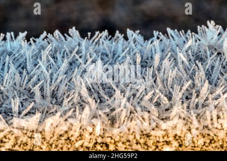 Nahaufnahme eines Makrofotos von Frost an einem kalten Wintermorgen auf einem Holztor. Stockfoto