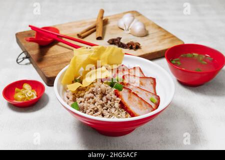 Sarawak Noodle Dry and Soup, Sarawak Mee Tai Bak und Sarawak Kway Teow in weißer Schüssel Draufsicht mit rohem Knoblauch, Löffel und Essstäbchen auf Holzschnitt Stockfoto