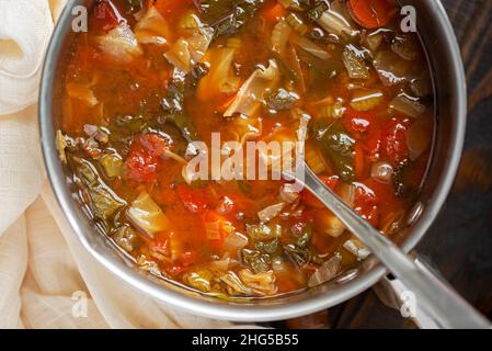 Nahaufnahme einer gesunden Kohlsuppe mit Karotten, Blattgemüse, Sellerie und Tomaten in einem Kochtopf Stockfoto
