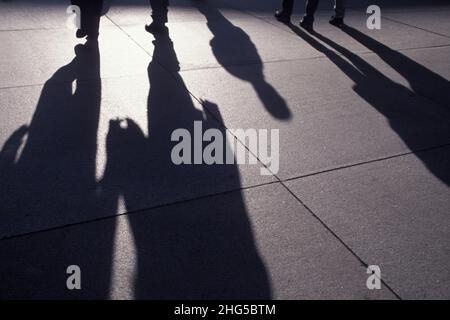 Verlängerte Schatten auf Gehwegen oder Gehwegen von Menschen, die gehen. Gruppe von nicht erkennbaren Pendlern in der Hauptverkehrszeit. New York City USA Stockfoto