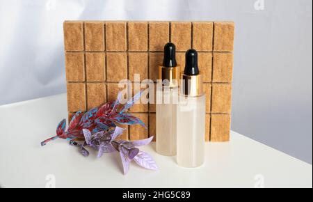 Zwei Flaschen mit Pipetten auf braunem Hintergrund. Serum, ätherische Öle oder flüssiges Kollagen, Hautpflegekonzept. Stockfoto