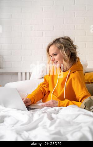 Fernunterricht Online-Bildung und Arbeit. Glückliche Frau Mädchen arbeiten Büro arbeiten Remote von zu Hause auf dem Bett Telefon mit Computer-Laptop reden. Stockfoto