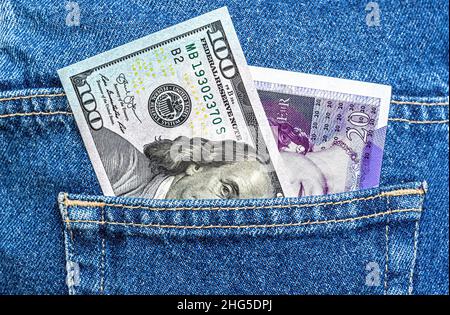 Amerikanische Dollar- und britische Pfund-Banknoten ragen aus der Jeans-Tasche Stockfoto