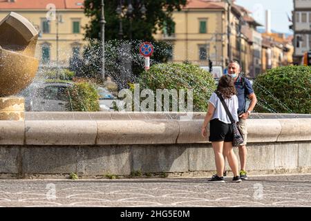 Pisa, Italien - 10. August 2021: Das Paar steht neben einem Brunnen in der Nähe des Bahnhofs Stockfoto