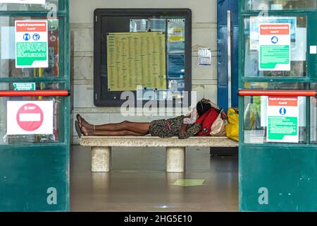 Pisa, Italien - 10. August 2021: Frau an einem heißen Tag, die Schatten findet und auf der Bank am Bahnhof liegt Stockfoto