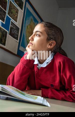 SCHÜLER MÄDCHEN TAGTRÄUMEN NACHDENKLICHE KLASSE ASIATISCH HISPANIC MÄDCHEN 12-14 Jahre Junior girl Student blickt aus der Schule Klassenzimmer Fenster, träumen. Stockfoto